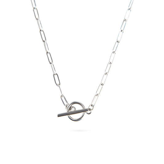 A studio shot on a white background shows the Lustrous Arc Necklace. This silver-toned necklace has a paperclip-style chain and a bold toggle clasp, which hangs as a central focal point.