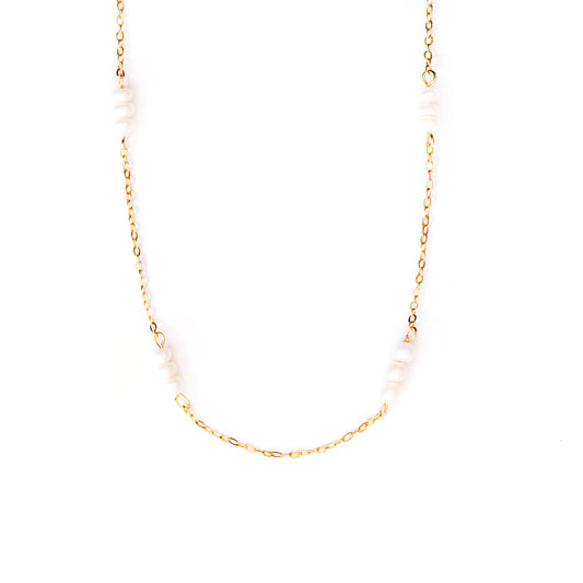 A studio shot on a pristine white background showcases the Lyra Pearl Chain Necklace. This gold-toned necklace features a delicate chain with small, irregularly shaped white pearls spaced along its length, forming a gentle U-shape.