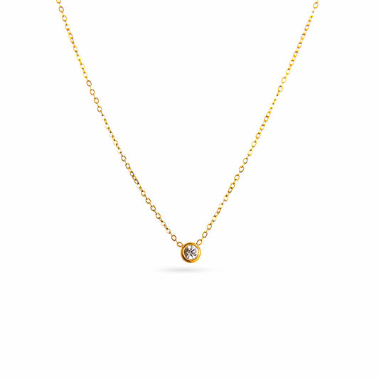 A studio shot on a pristine white background displays the Parker Spheroid Necklace. This gold-toned necklace has a fine chain that forms a gentle V-shape, suspending a single, round, bezel-set gemstone.