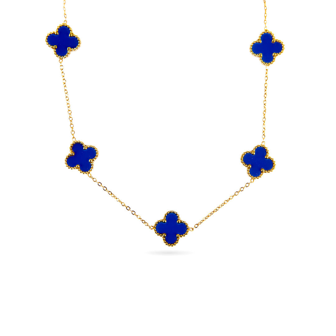 A studio shot on a white background displays the Aurora Clover Pendant. This gold-toned necklace features a delicate chain with five evenly spaced clover-shaped pendants, each filled with a vibrant blue enamel.