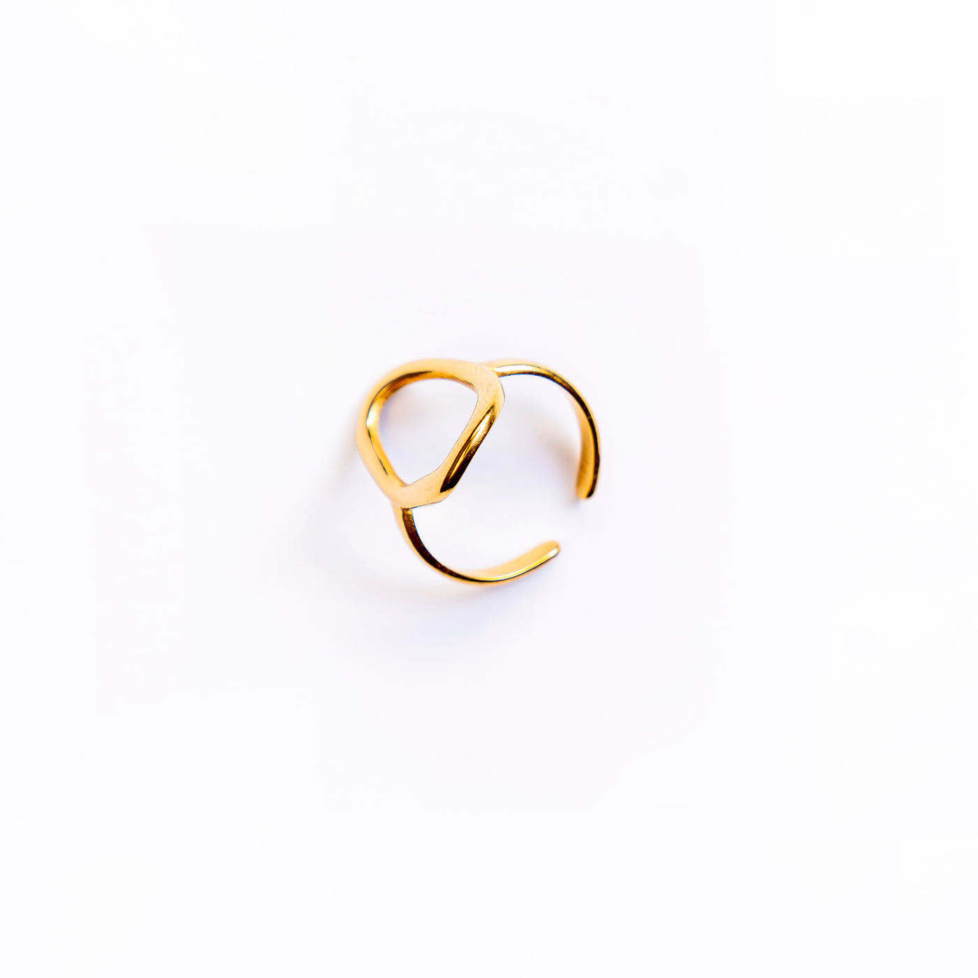 A studio shot on a pristine white background displays the Chloe Open Teardrop Ring. This gold-toned ring features a polished, abstract open teardrop shape, with one end extending to form an adjustable band.