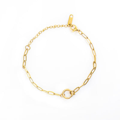 The Elara Loop Bracelet is laid out in a circular shape on a white background. This gold-toned bracelet features an elongated paperclip-style chain that connects to a prominent, polished circular clasp at its center, with an extender chain near the lobster claw closure.
