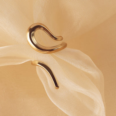  Lila Eternity Band by Delta Jewel, a sculptural open-ended gold-plated ring with a fluid, organic form, displayed on soft beige fabric.