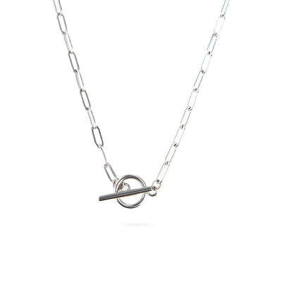 A studio shot on a white background shows the Lustrous Arc Necklace. This silver-toned necklace has a paperclip-style chain and a bold toggle clasp, which hangs as a central focal point.
