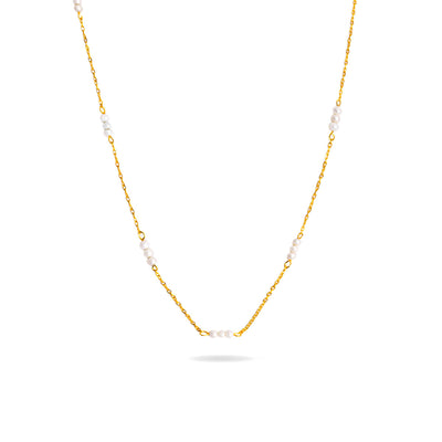 A studio shot on a pristine white background displays the Lyra Pearl Chain Necklace. This gold-toned necklace hangs and forms a gentle curve, with small, white pearls spaced along its delicate chain.