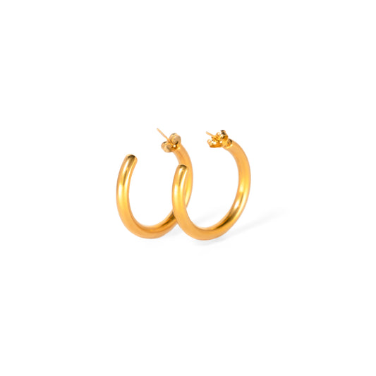 A studio shot on a clean white background displays a pair of Marina Bold Hoops. Each gold-toned earring is a thick, highly polished, C-shaped hoop with a post backing.