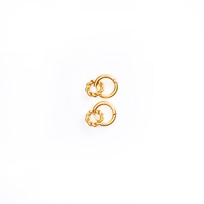 A studio shot from above against a white background shows a pair of gold-toned Penelope Knot Hoops earrings. Each earring features a smooth, circular hoop with a smaller, intricately textured or braided gold ring suspended within its lower curve.