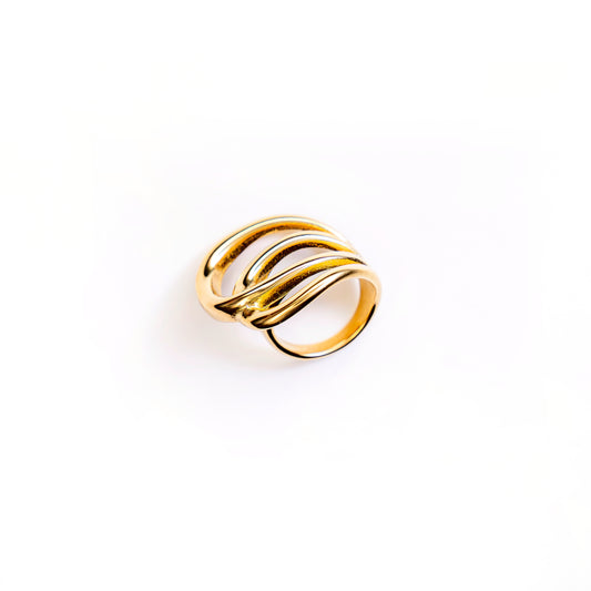 A studio shot on a bright white background displays the Seraphina Wave Ring. This gold-toned ring features multiple intertwining bands that form a bold, undulating, wave-like design, with a high-polished finish.