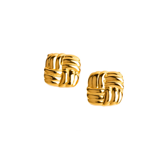 A studio shot on a clean white background displays a pair of Venus Knot Studs. The gold-toned earrings are rendered as a small, square-shaped knot, with their polished, shiny surface reflecting the light.