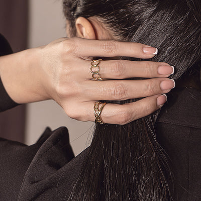 Close-up of a hand adorned with an 18k gold plated Juliette French Ring, showcasing its intricate design and golden luster.