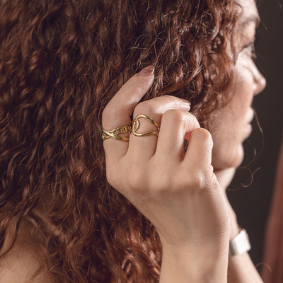 Seraphine Charm Ring and Juliette French Ring by Delta Jewel, a sculptural gold-plated design, worn on the fingers.